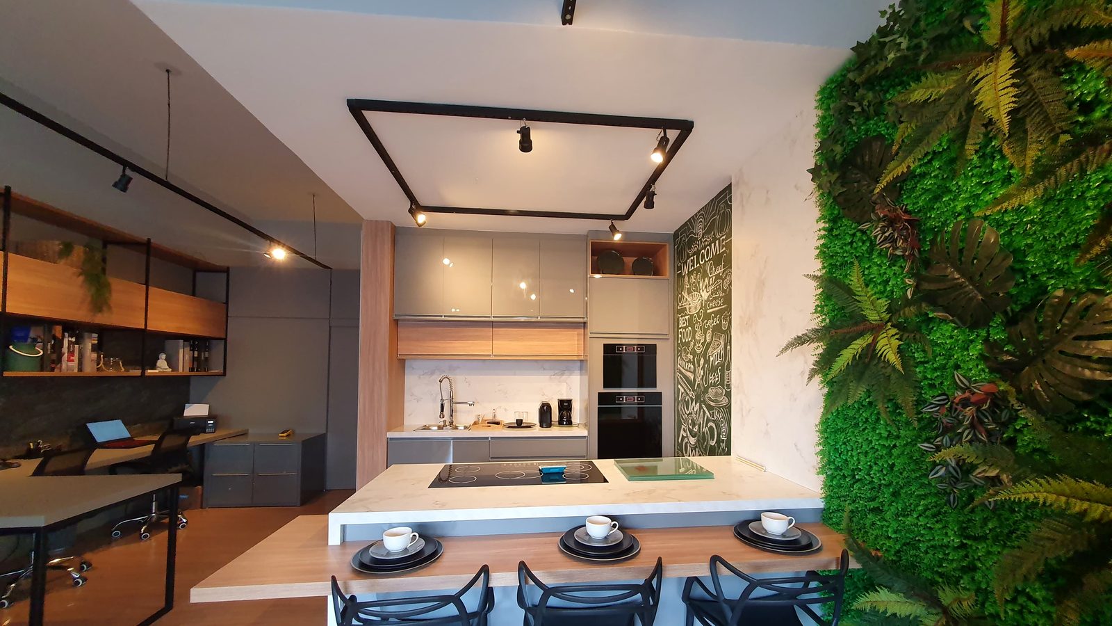 Showroom da Di Pieva em Marília: cozinha planejada com ilha em pedra clara, armários cinza e madeira, e parede verde ao lado