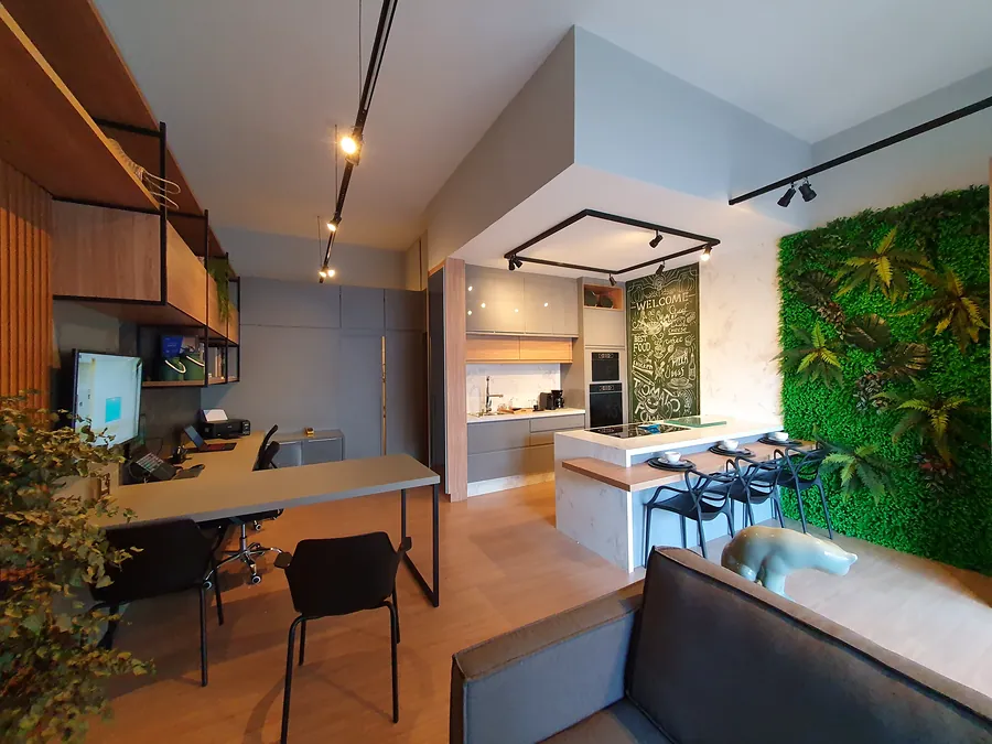 Visão geral do showroom: estação de trabalho em madeira, cozinha e parede verde